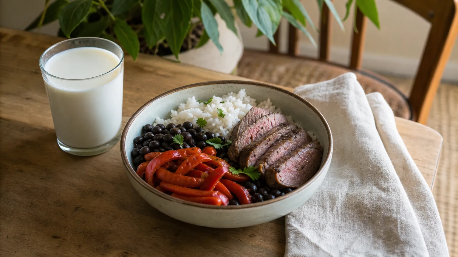 A generous dinner bowl of rice, sliced steak, black beans and roasted peppers with a glass of milk